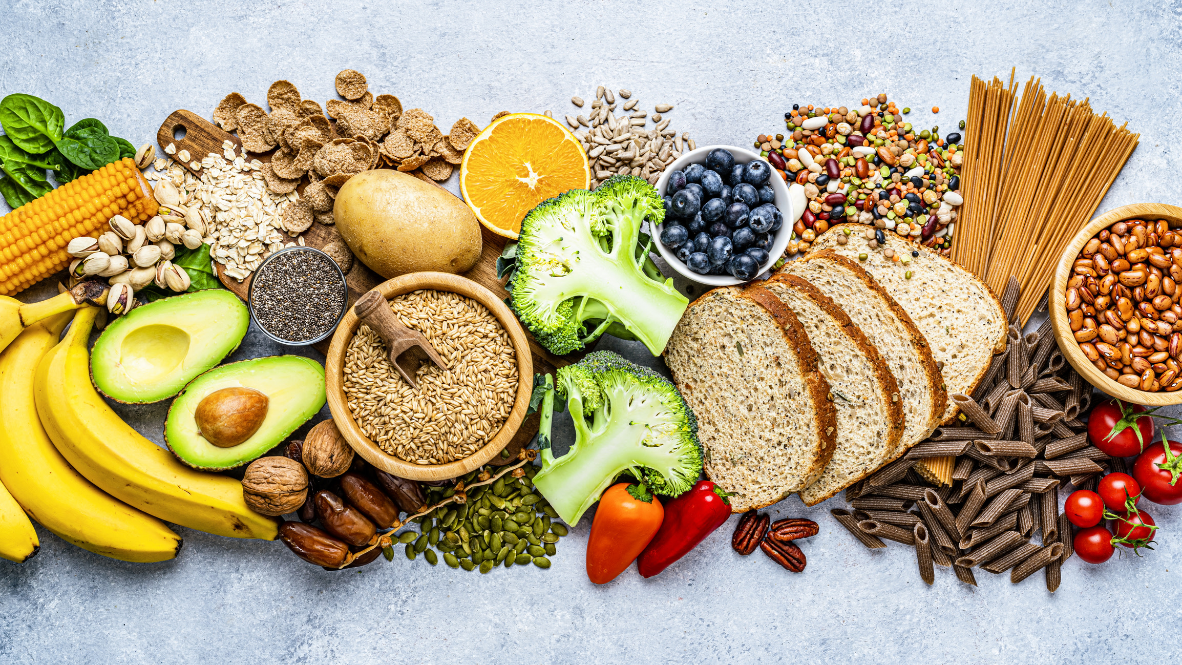 Nuts, beans, wholegrains, vegetables and fruit laid out on a table, the everyday foods behind losing belly fat naturally