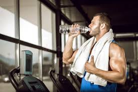 Man drinking bottled water at the gym, plain water being the only thing allowed during a water fast