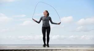 Woman skipping with a rope on a seafront path