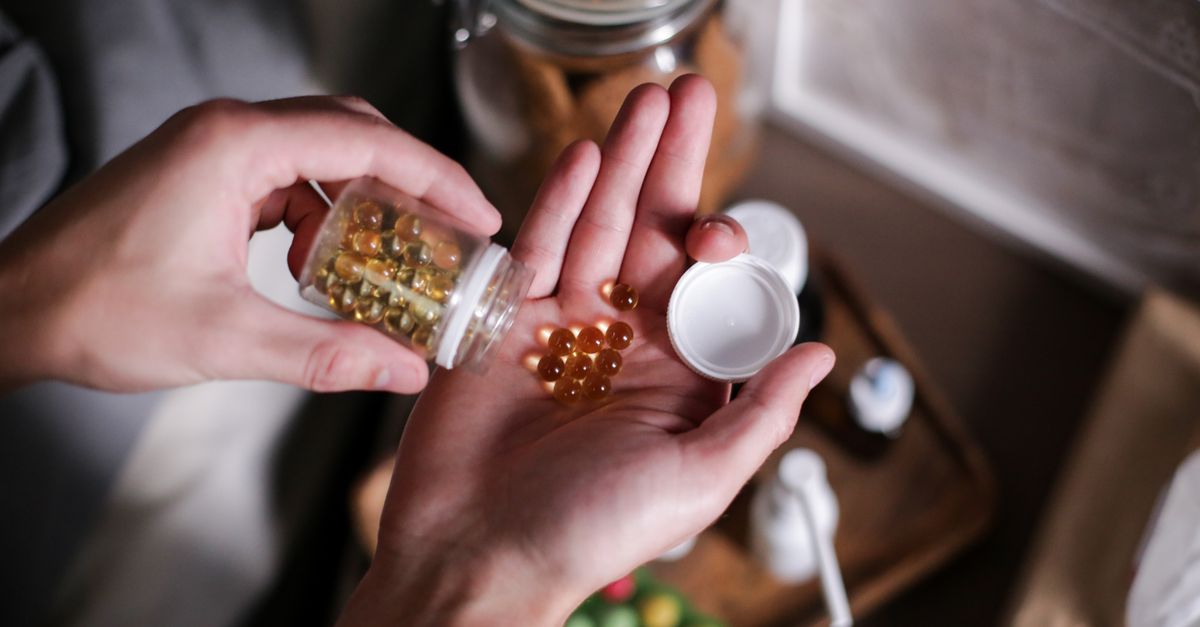 A person tipping supplement capsules from a bottle into their palm, the everyday routine behind apple cider vinegar pills