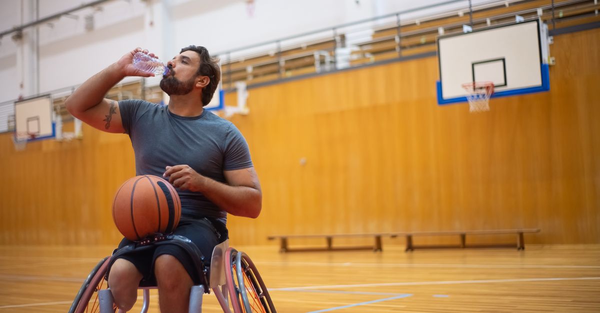 Wheelchair basketball player sipping water from a bottle on an indoor court, an athlete rehydrating