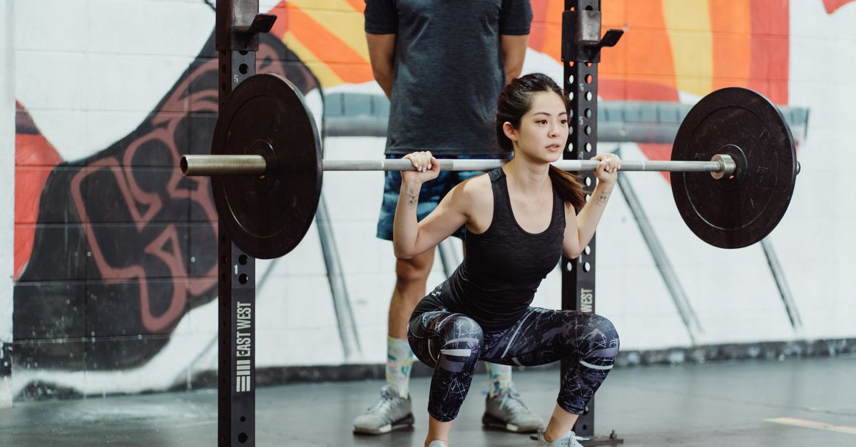 Woman squatting with a barbell in a gym rack, the lifting half of a cardio and weights session