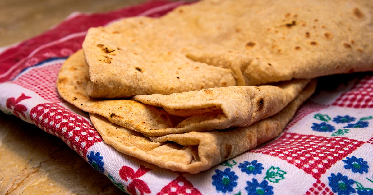 A stack of folded whole wheat chapatis resting on a cloth