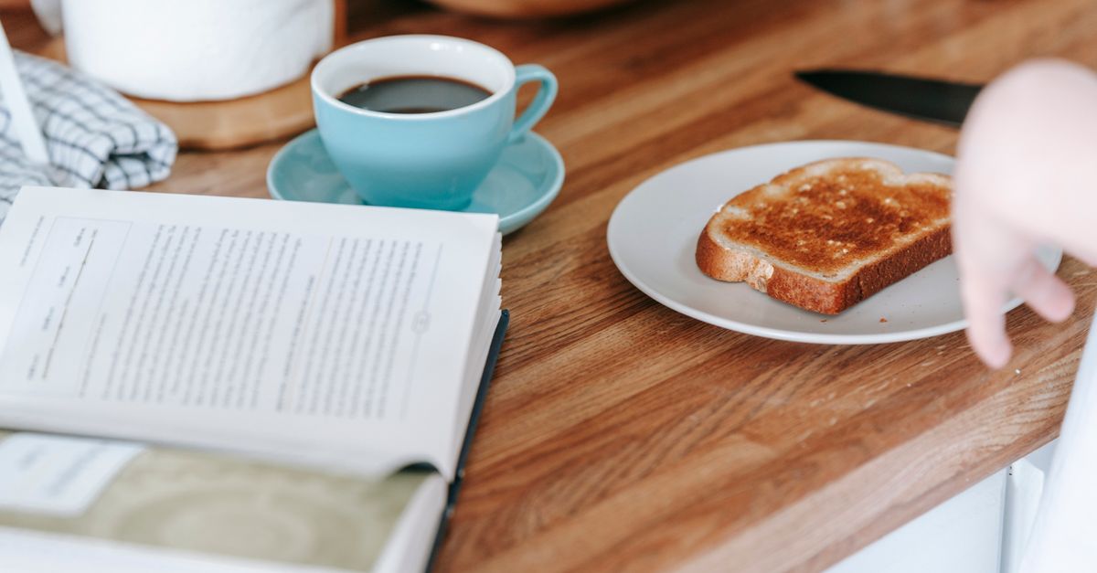Toast and a cup of coffee beside an open book, the breakfast blamed for a slow metabolism