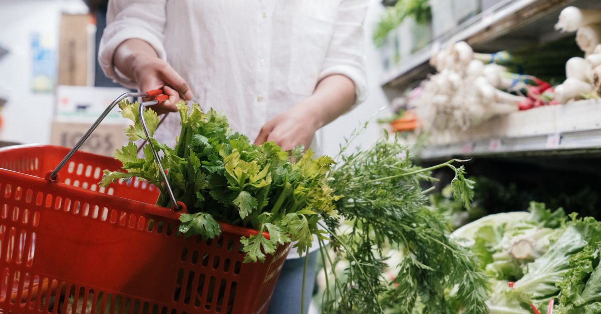 Shopper carrying a basket of fresh greens at a market, changing what you eat to hold a calorie deficit