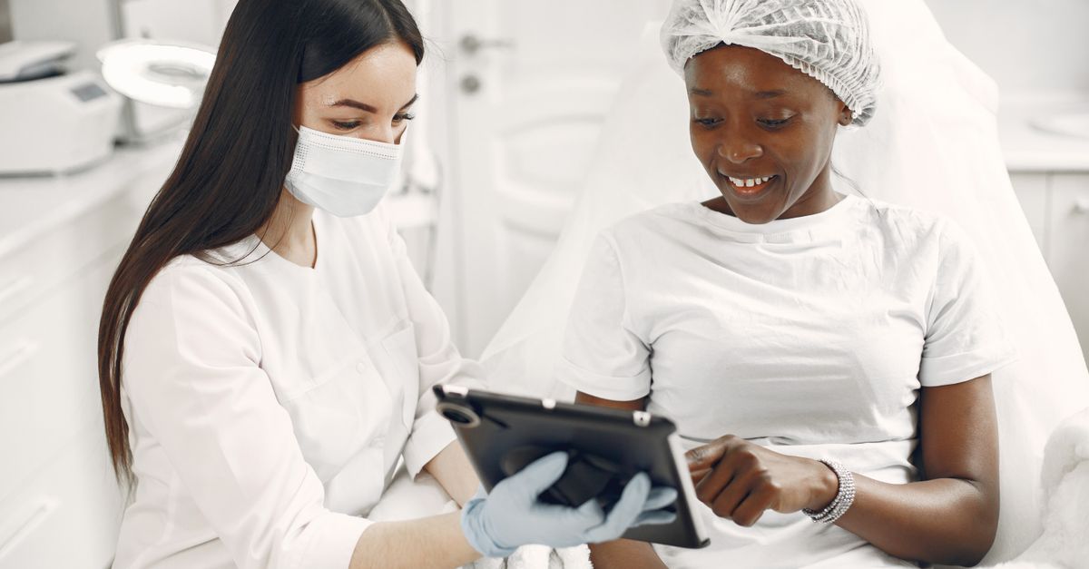 A dermatologist and a patient reviewing skin together during a clinic consultation about loose skin after weight loss