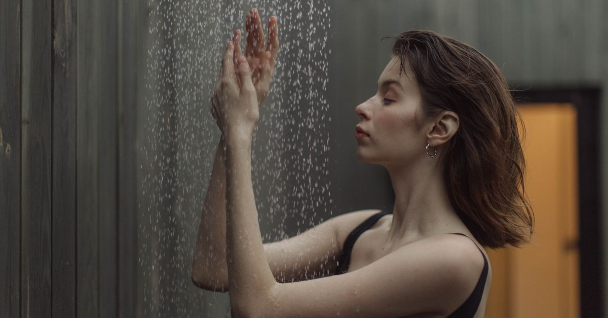 Woman standing under a stream of cold running water, the gentler everyday alternative to an ice bath
