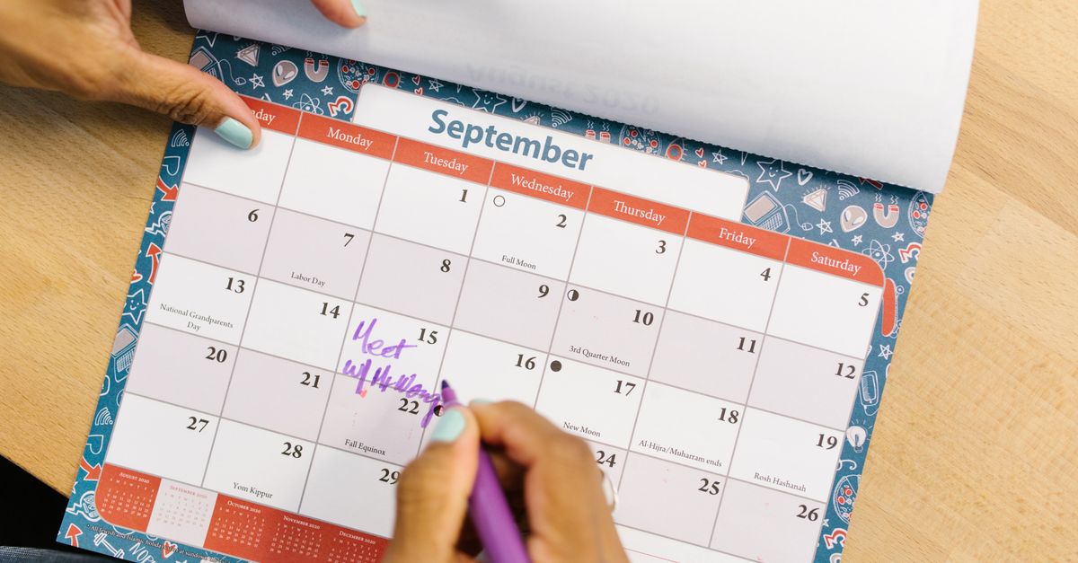 Hand marking dates on a paper calendar, tracking the days around a period when energy drops