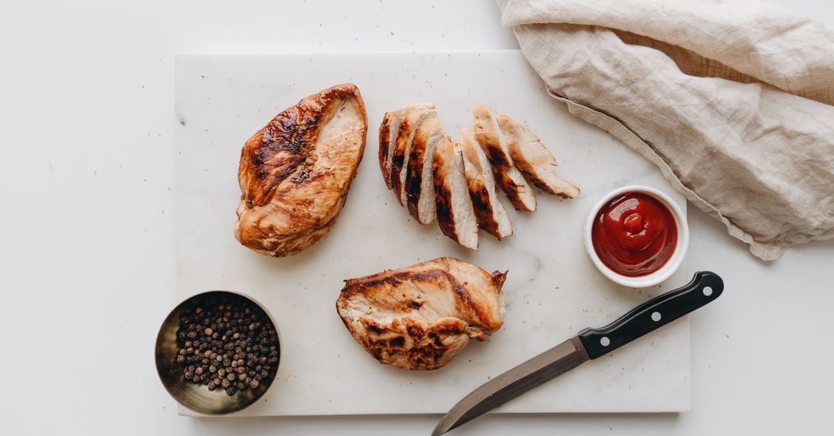 Sliced grilled chicken breast on a wooden board