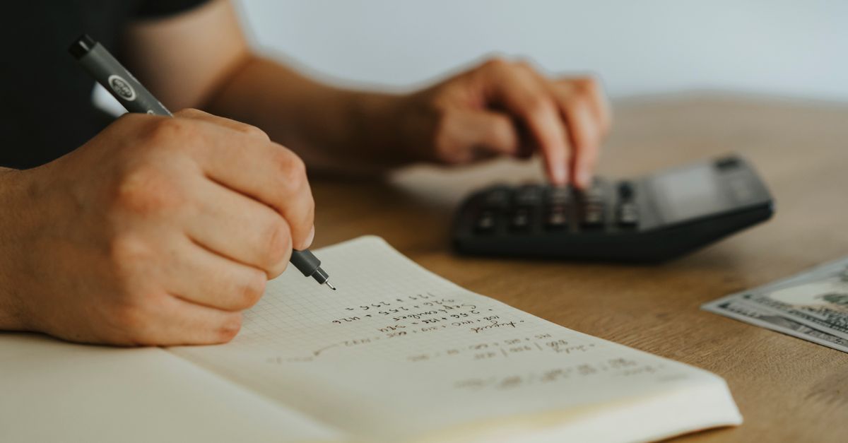 Hands working out calculations in a notebook beside a calculator, the arithmetic behind losing 5 pounds a week