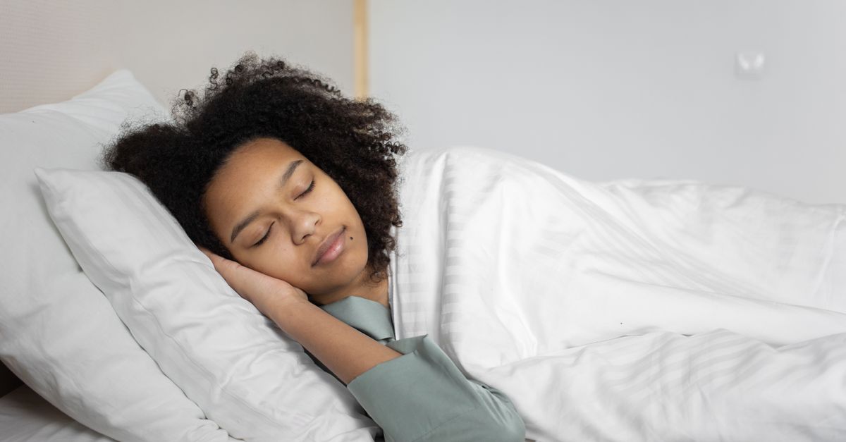 Woman asleep in bed in soft morning light, the sleep that keeps food noise and hunger hormones in check