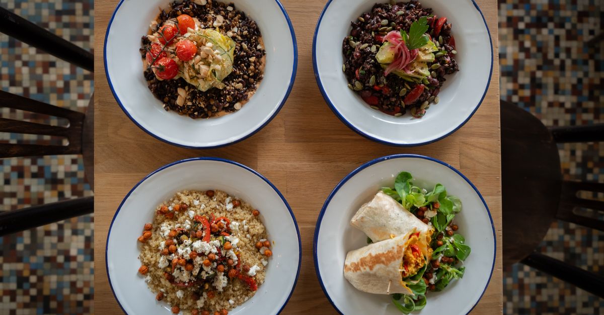 Bowls of grains, beans and fresh vegetables on a wooden table
