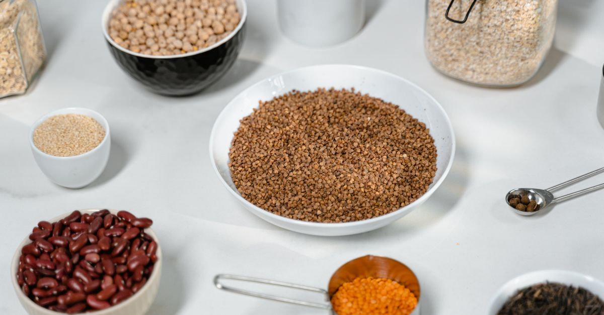 Bowls of dried beans, lentils and whole grains on a pale counter, the fibre gut bacteria ferment for metabolism