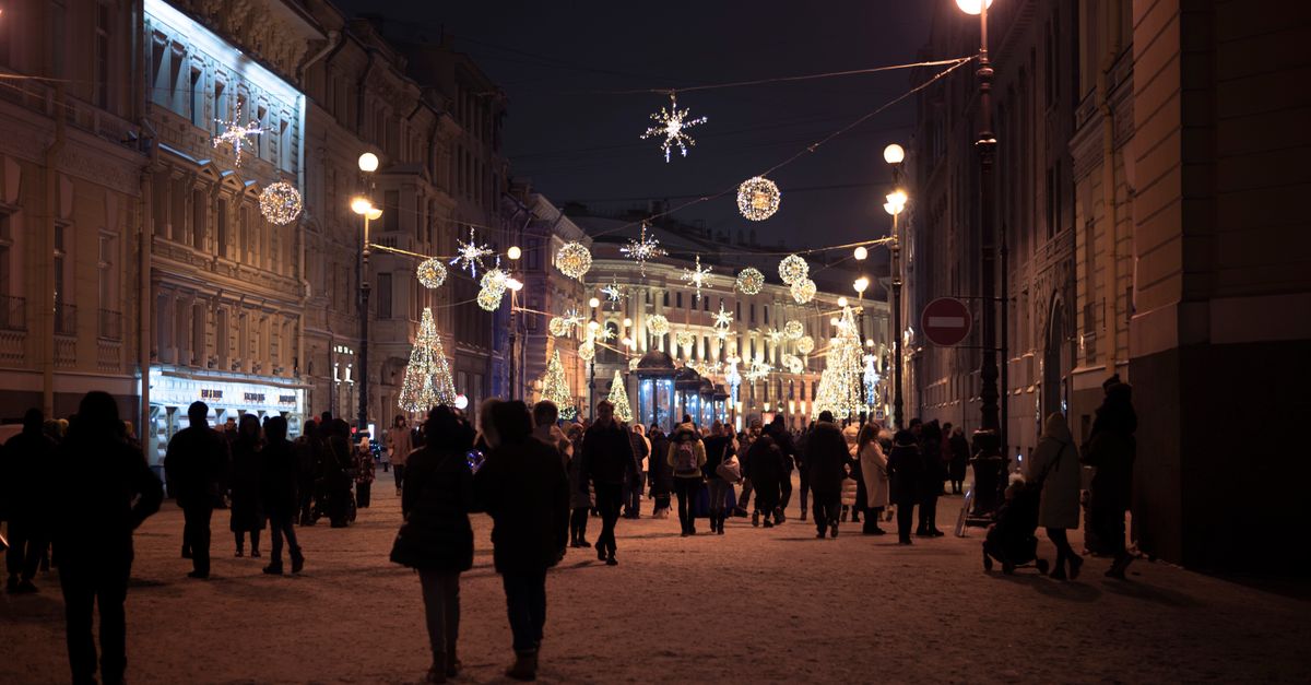Crowds walking a snowy street under festive lights, the weeks measured for holiday weight gain