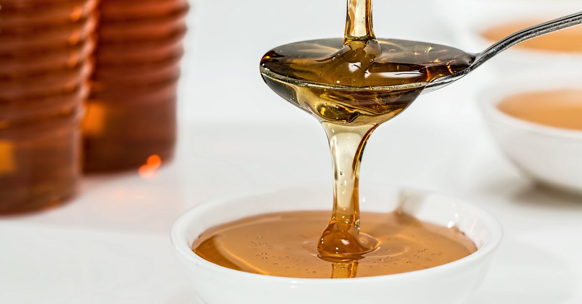 Honey pouring from a spoon into a white bowl, counted as free sugars when you stop sugar