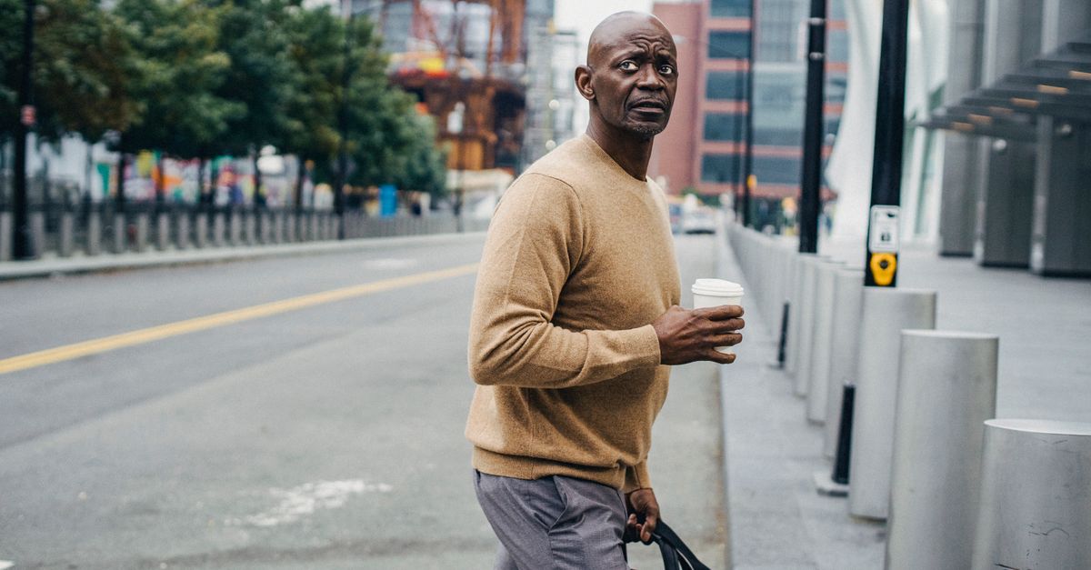 Man walking along a city street with a coffee, the daily movement that dwarfs any BMR change.