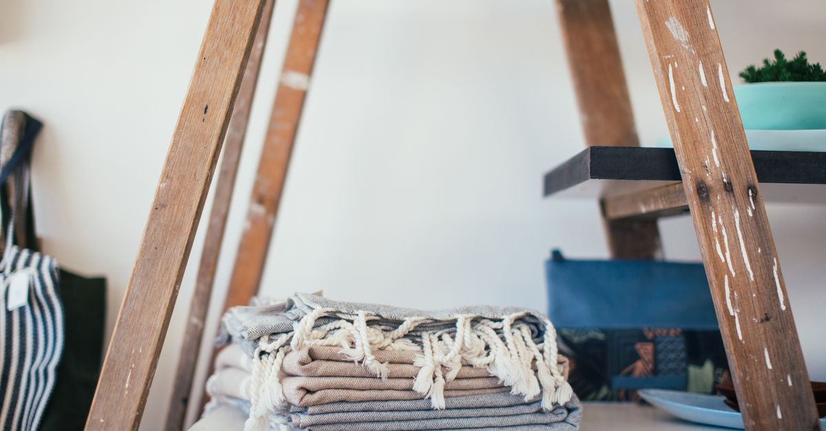 Folded soft cotton textiles stacked on a wooden shelf, breathable fabrics that reduce apron belly irritation