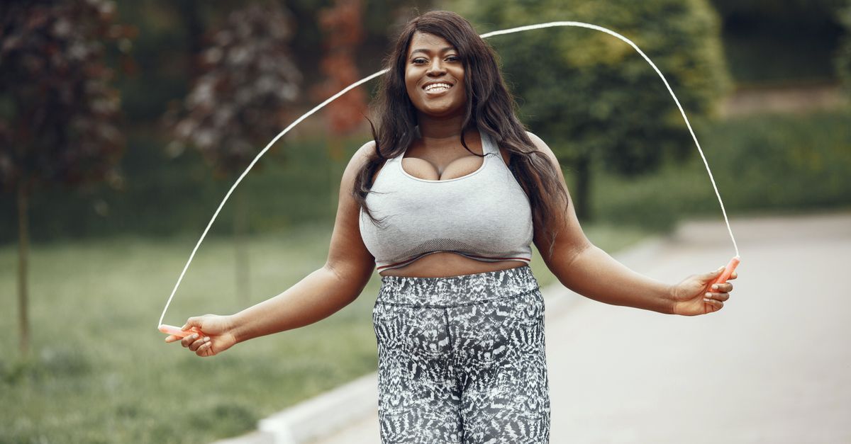 Smiling woman mid skip with a jump rope in a sunny park during a 30 day challenge