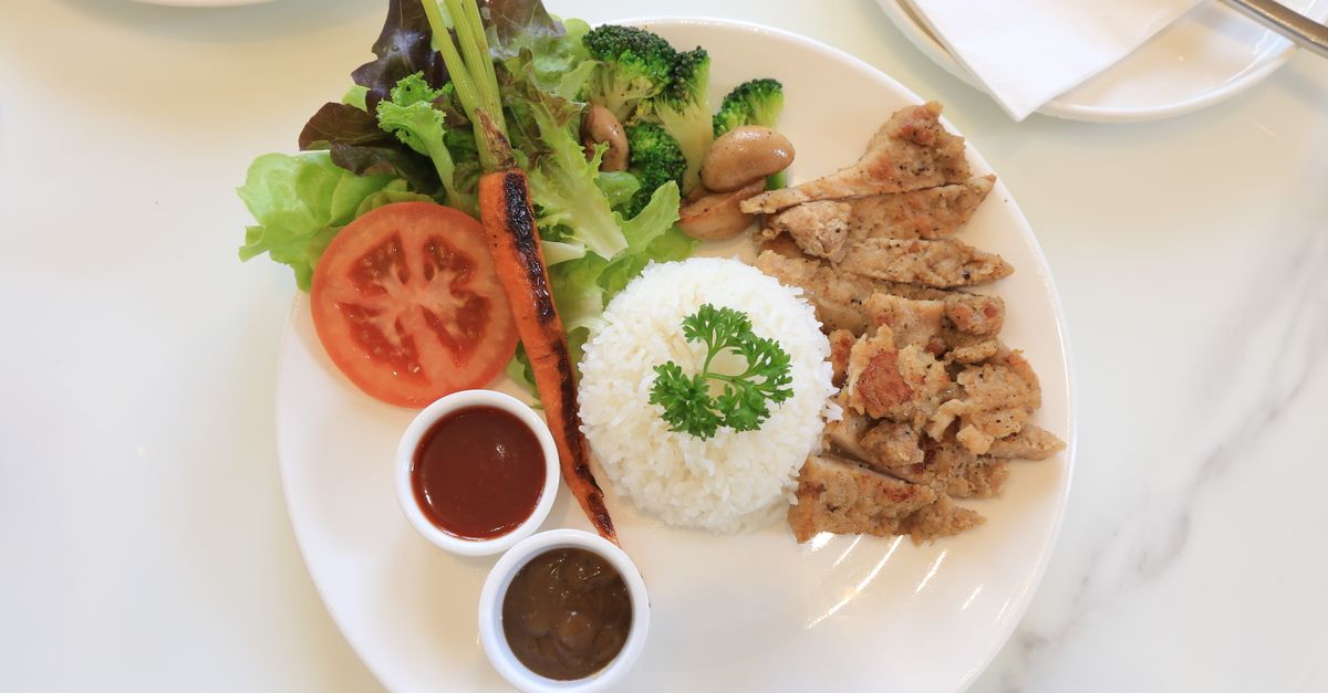 Plate of grilled chicken, rice and fresh vegetables, the energy intake side of a jump rope weight loss challenge