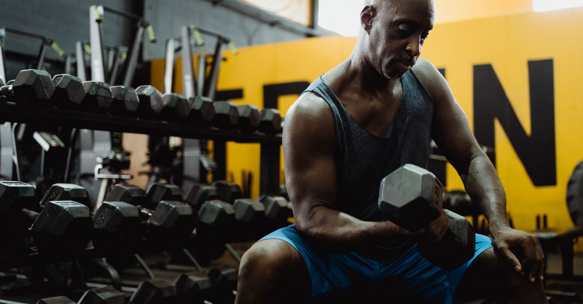Man lifting a dumbbell in a gym, the kind of training demand that L-carnitine supplements are marketed to support