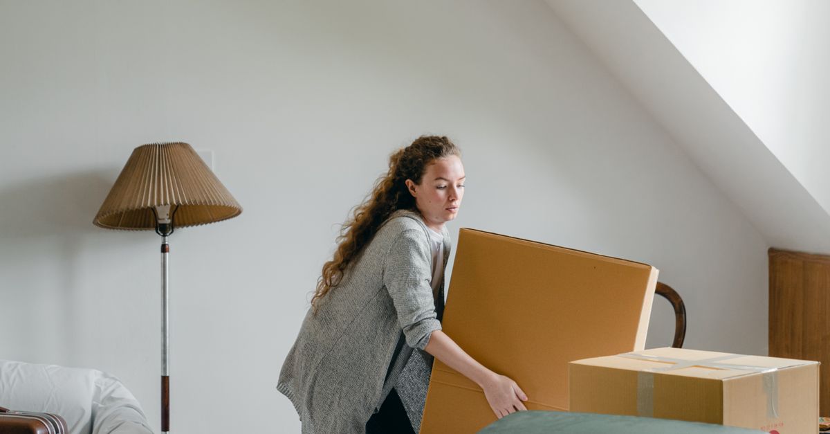 A woman bending to lift a box at home, the everyday trunk work a plank trains