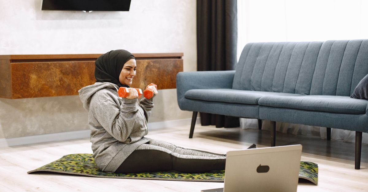 Woman doing dumbbell exercises on a mat at home, the activity habit that keeps weight off