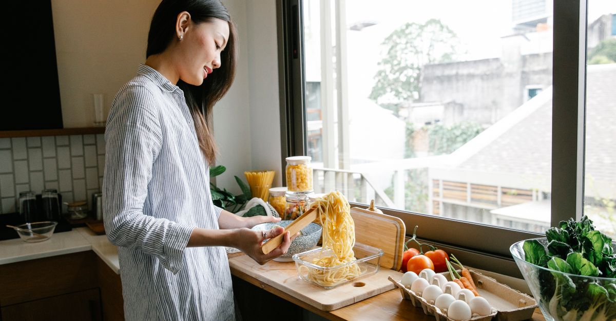 Woman preparing vegetables at a sunlit kitchen counter while managing weight with PCOS