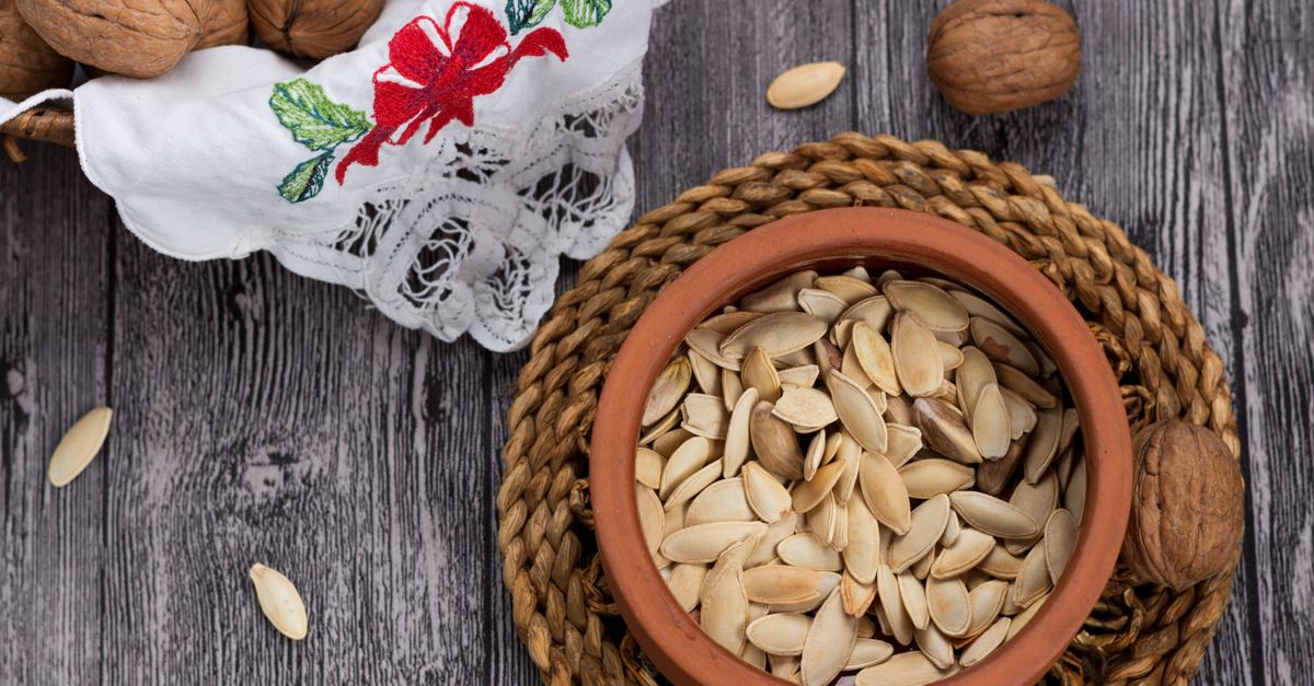 Pumpkin seeds and walnuts in a terracotta bowl on wood, food sources of magnesium