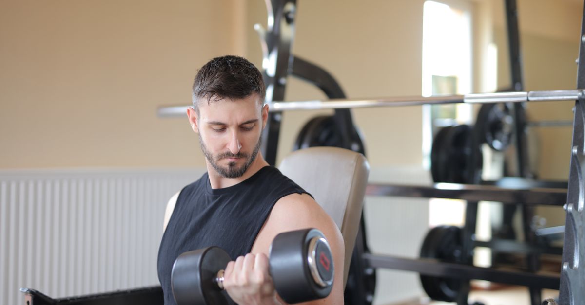Man curling a dumbbell in a gym, the strength training that protects muscle while losing weight
