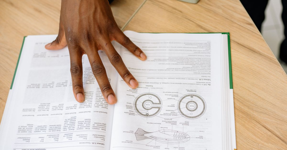 A hand resting on an open research paper of the kind that reports metabolism supplement trials