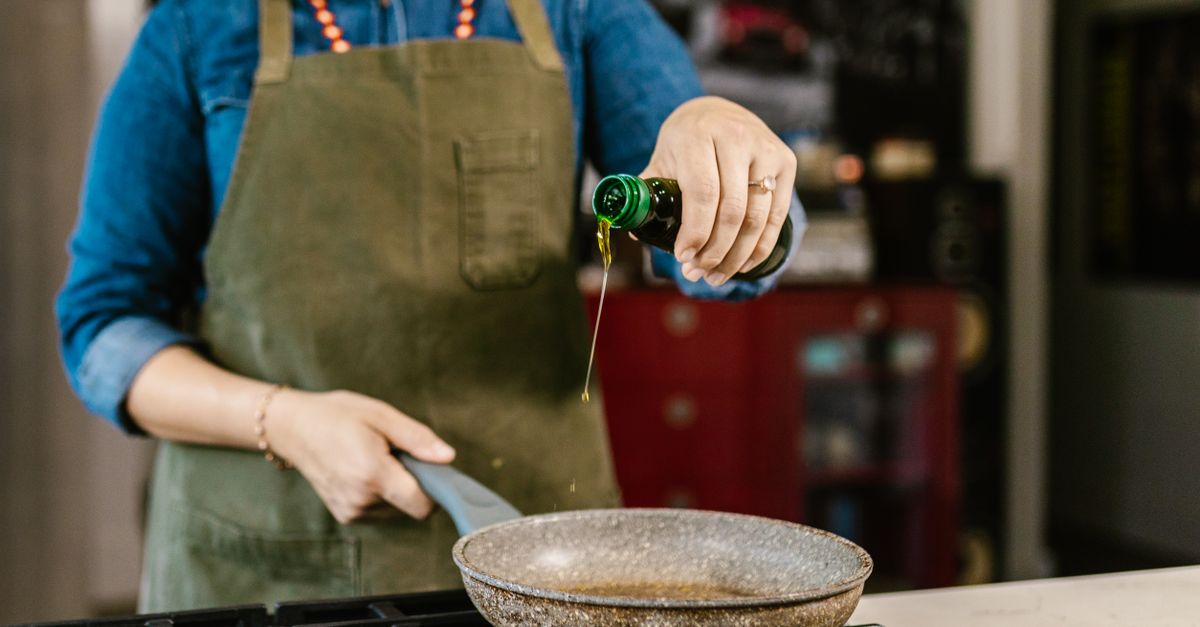 Cook pouring extra virgin olive oil into a hot frying pan instead of butter