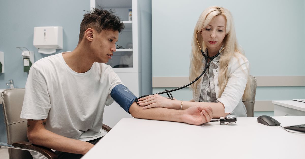 A doctor measuring a young man's blood pressure in a clinic