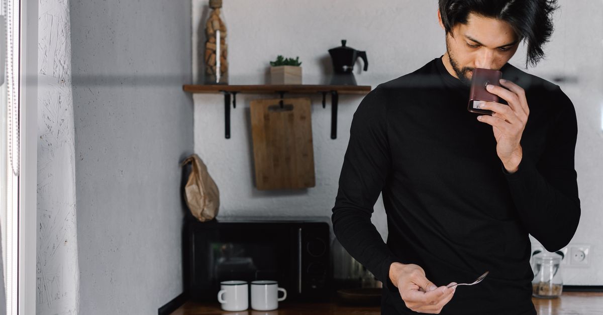 Man sipping coffee in his kitchen, the fasting hours before the day's one meal on OMAD