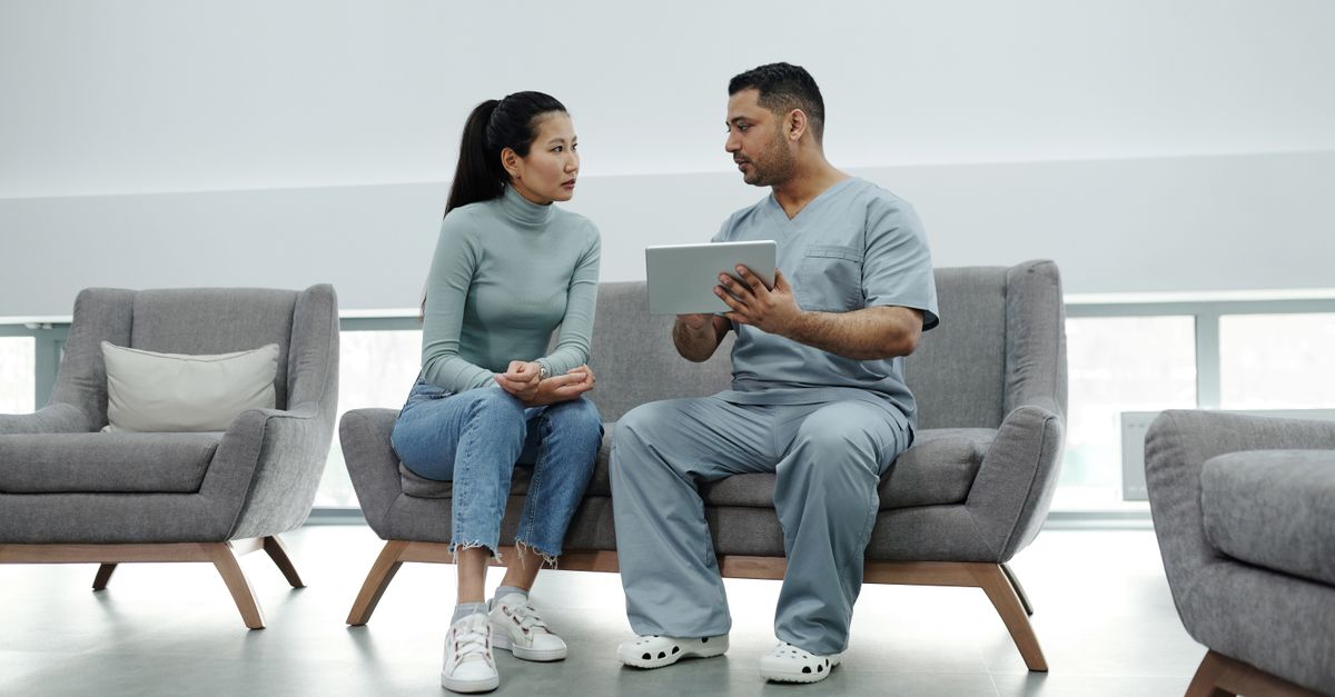 Woman talking with a clinician in scrubs during an appointment, the questions worth raising about PCOS