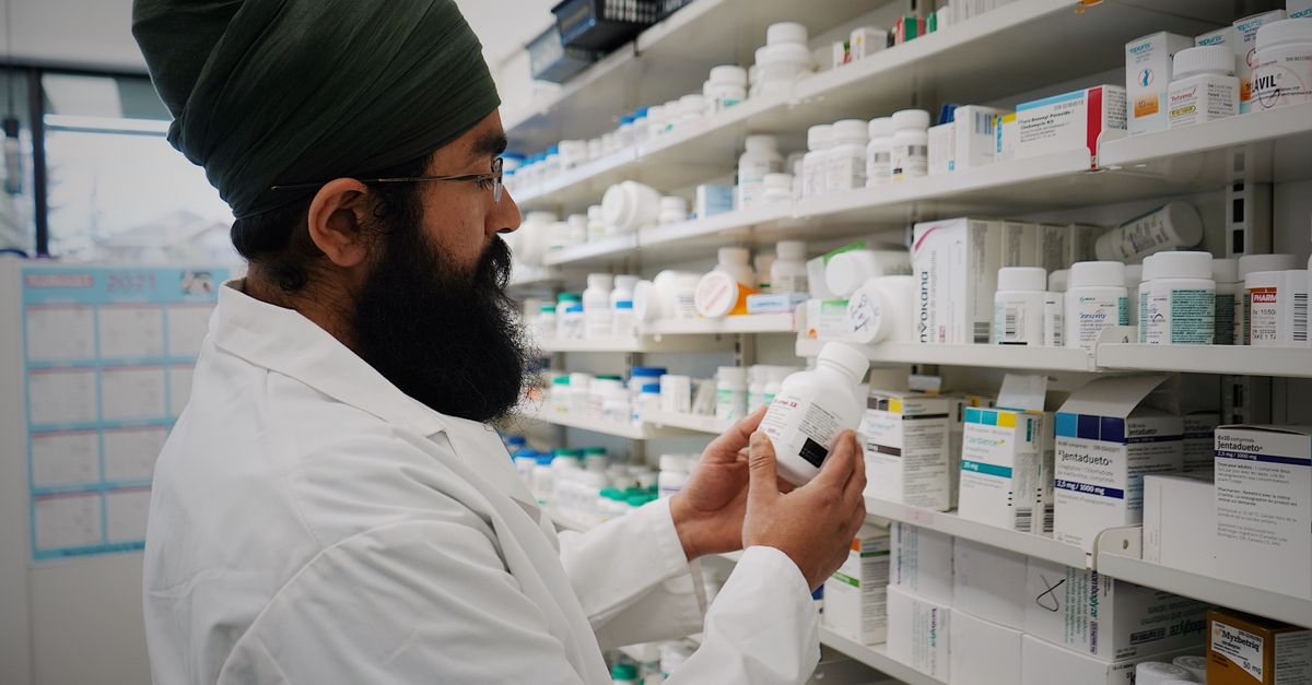 Pharmacist checking a bottle while stocking pharmacy shelves, where an effervescent tablet is one format among many