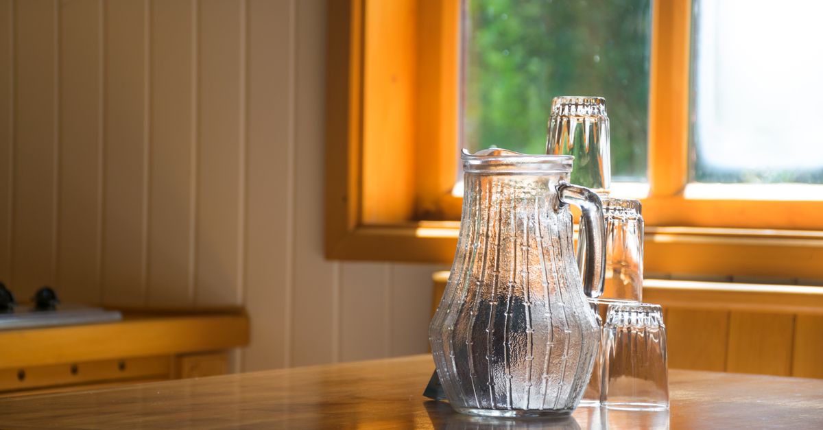 Glass jug of water and tumblers on a kitchen table, hydration topped up hours before a workout