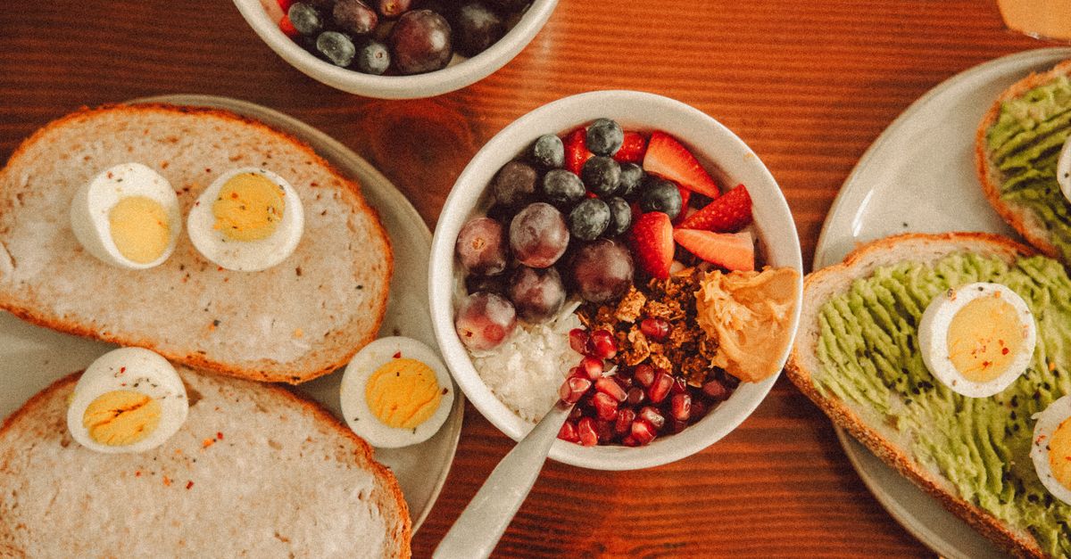 Halved boiled eggs on bread beside a bowl of oats and berries, a breakfast carrying protein and fibre