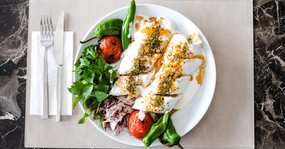 White plate of grilled chicken with salad leaves and tomatoes