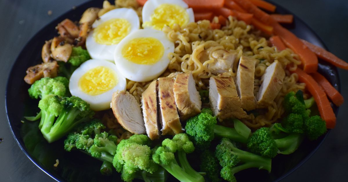 Plate of sliced chicken, boiled eggs, broccoli and noodles