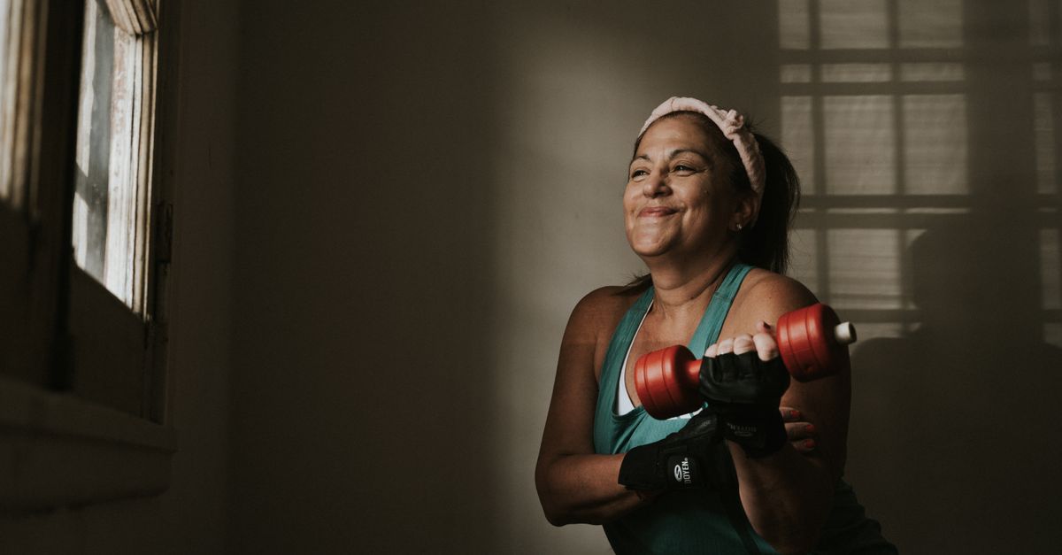 A woman lifting a pair of dumbbells at home