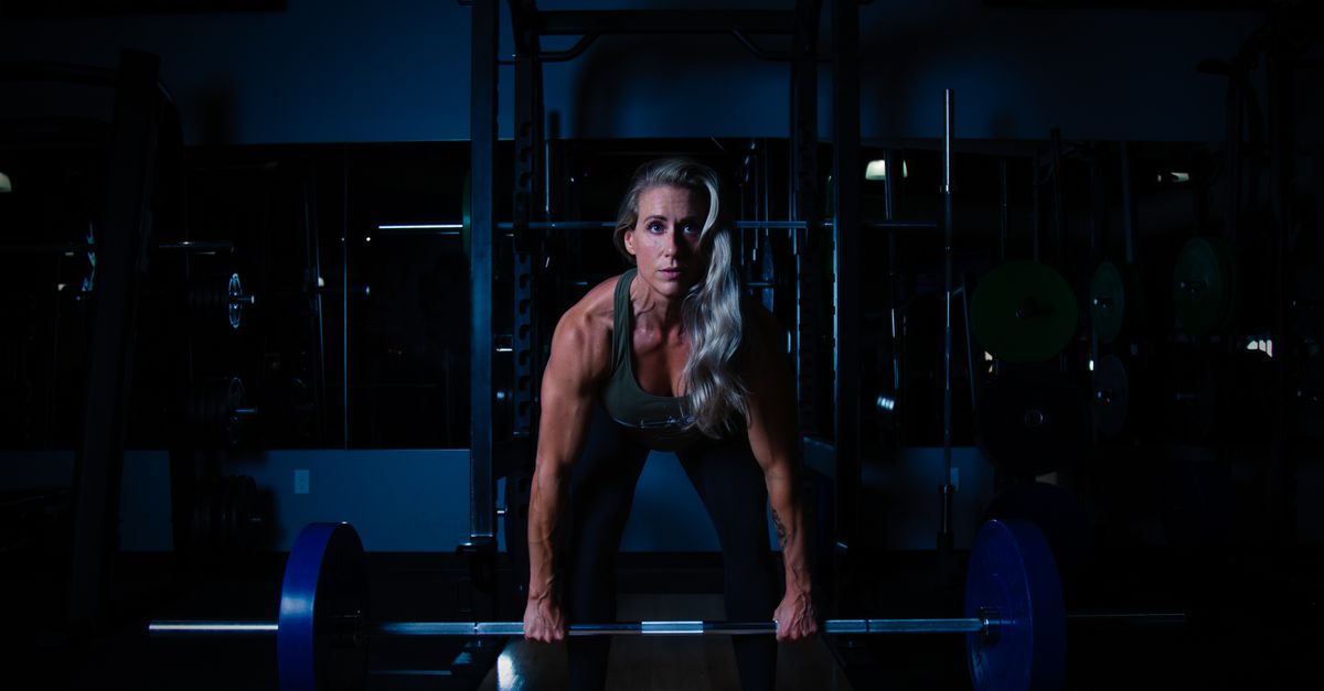 Grey haired woman lifting a barbell in a gym, the resistance training that improves insulin sensitivity