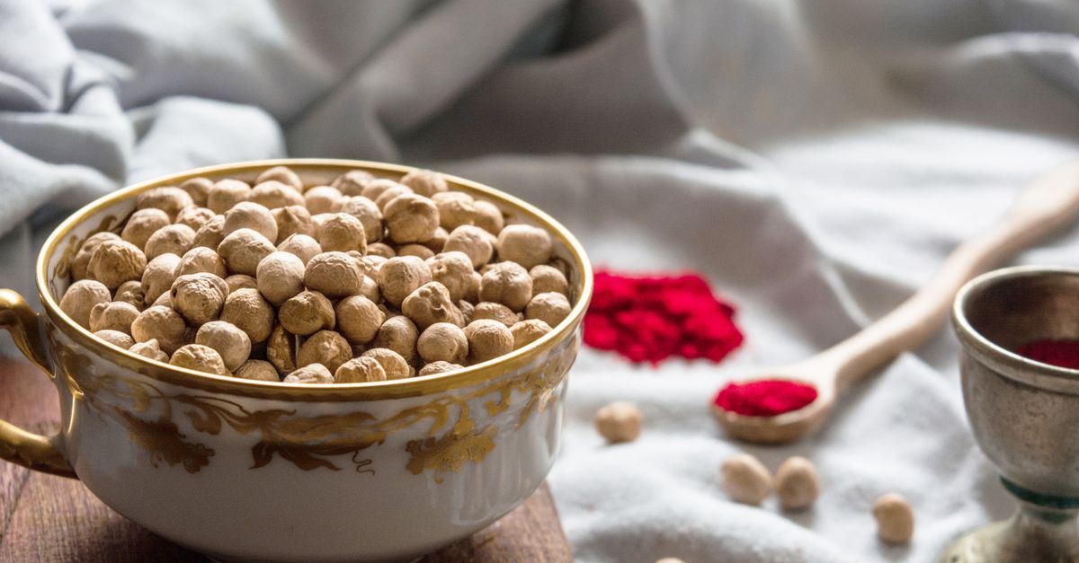 Bowl of chickpeas beside small dishes of ground spice, the roasted gram that sattu protein flour is milled from
