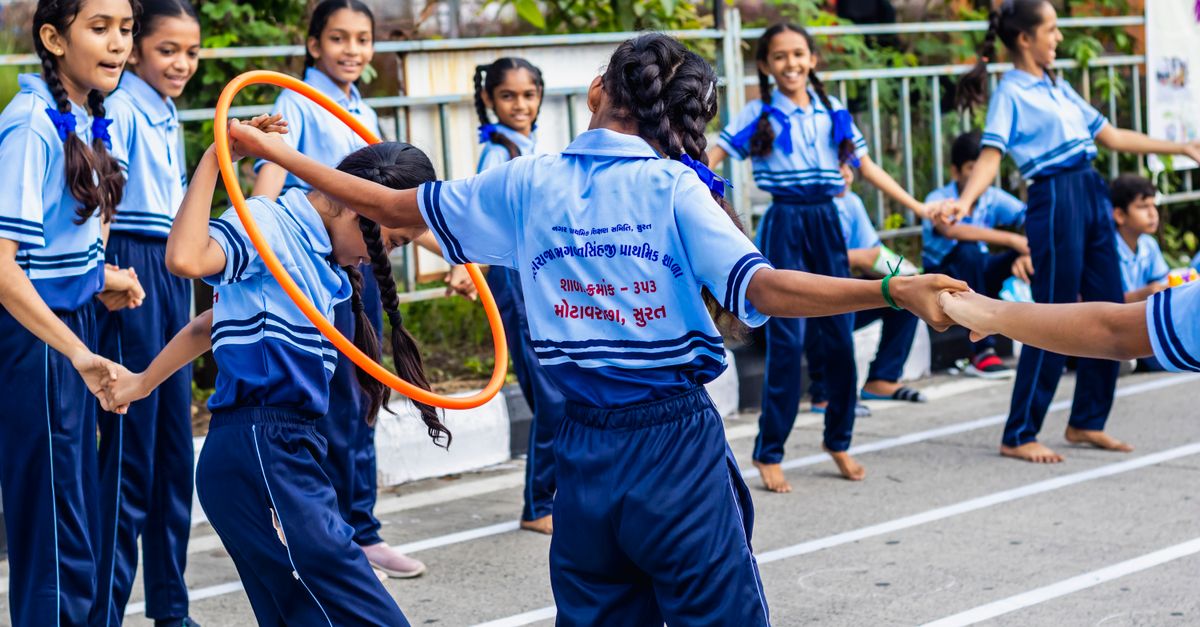 Schoolchildren in blue uniforms playing a hoop game outdoors, everyday movement and childhood obesity in India