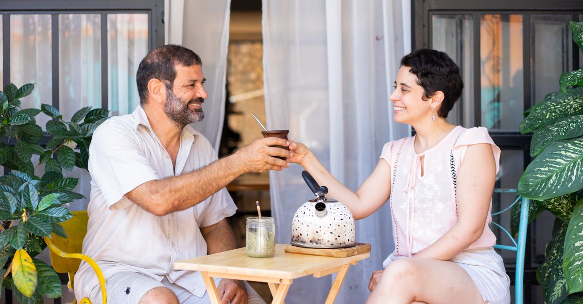 Two people sharing a mate gourd and thermos outdoors, how yerba mate is usually drunk