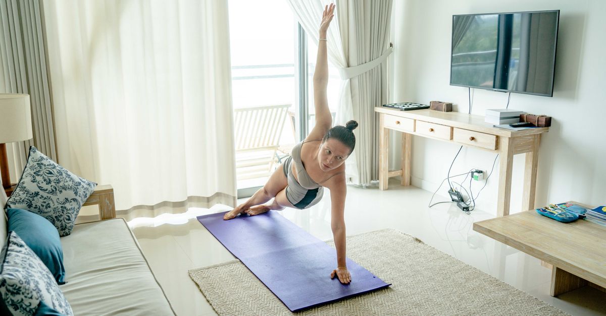 Woman holding a side plank on a living room mat, training the obliques a standard plank leaves out