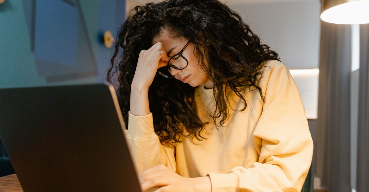 Woman at a laptop pressing her forehead, the poor concentration that can follow skipping breakfast