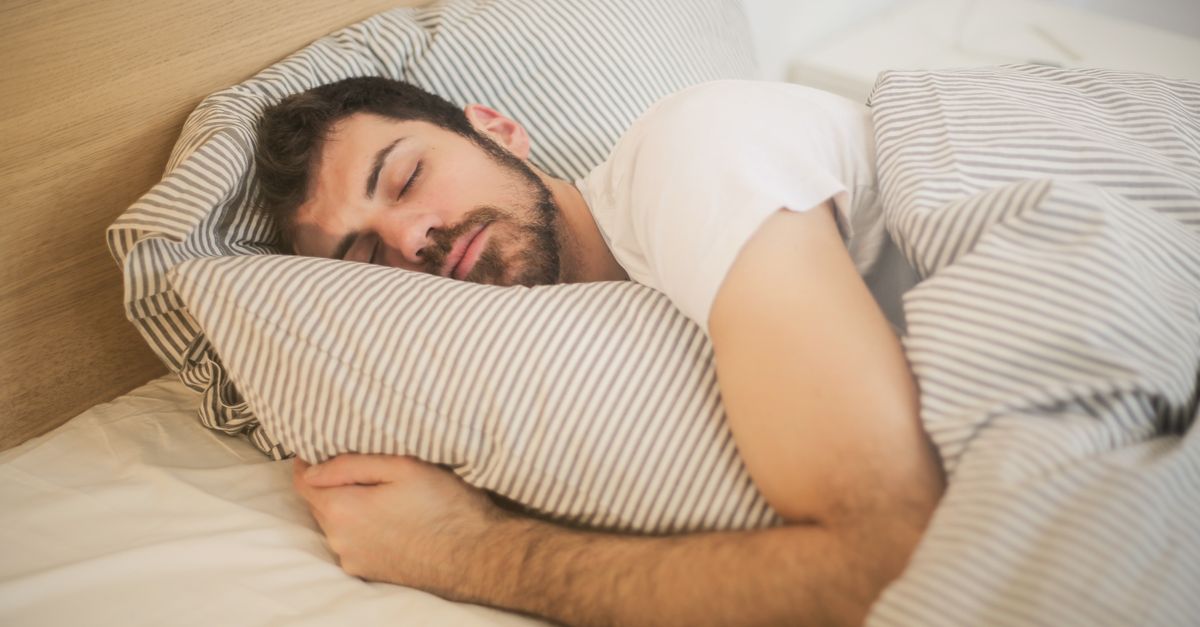 Man sleeping peacefully on striped bedding in morning light, the sleep side of metabolism after 30
