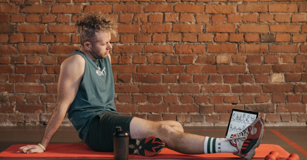 Man sitting on a gym mat catching his breath after a Tabata training session