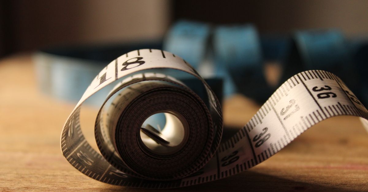 Soft tape measure unrolled on a wooden table, a better guide to love handles than the mirror