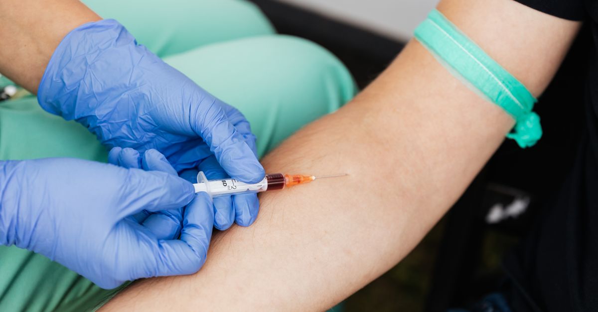 Gloved hand drawing a morning blood sample from an arm, the test used to confirm low testosterone